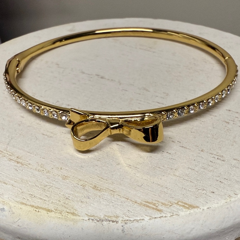 Kate Spade Gold Plated Iconic Bow Bangle Bracelet surrounded by Tiny Crystals.